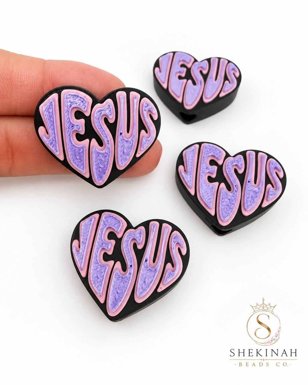 Bead 3D en forma de corazón con la palabra JESUS en rosa y lila sobre fondo negro, Shekinah Beads Co.